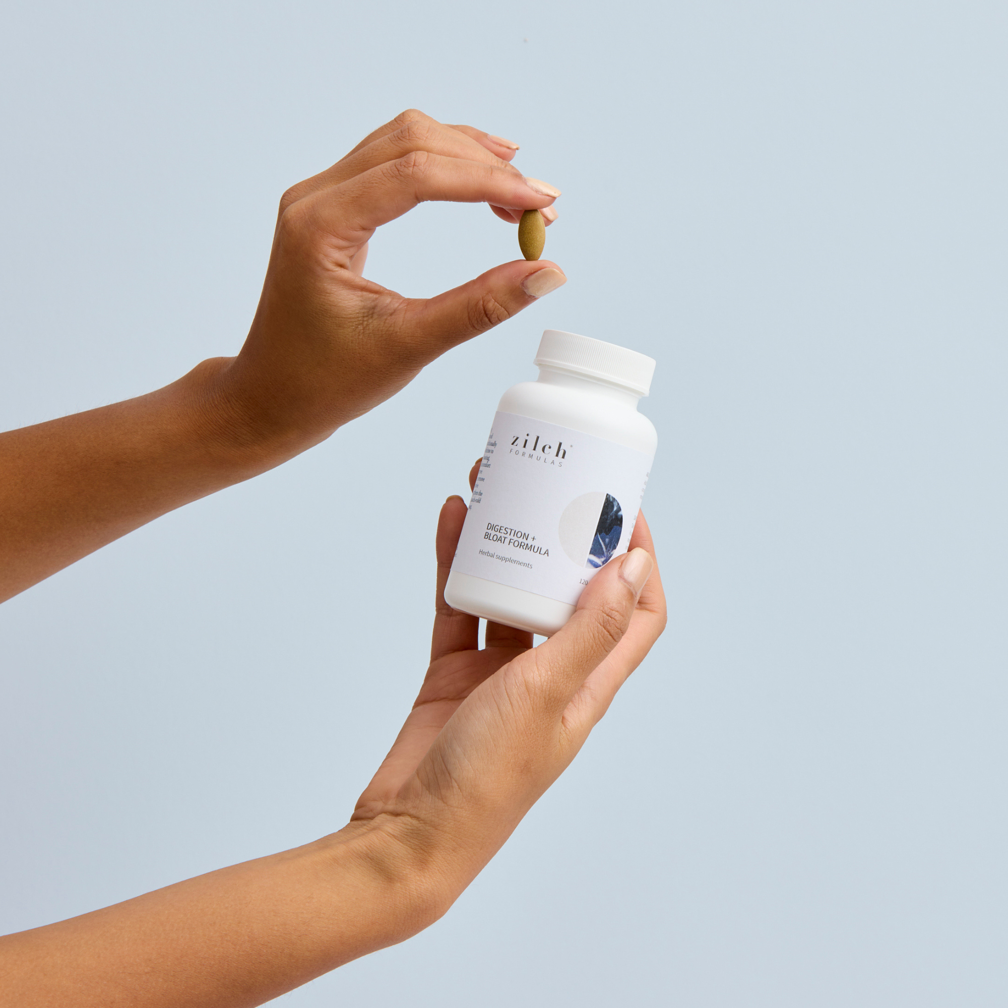 Zilch digestion and bloat formula and tablet held by female hand